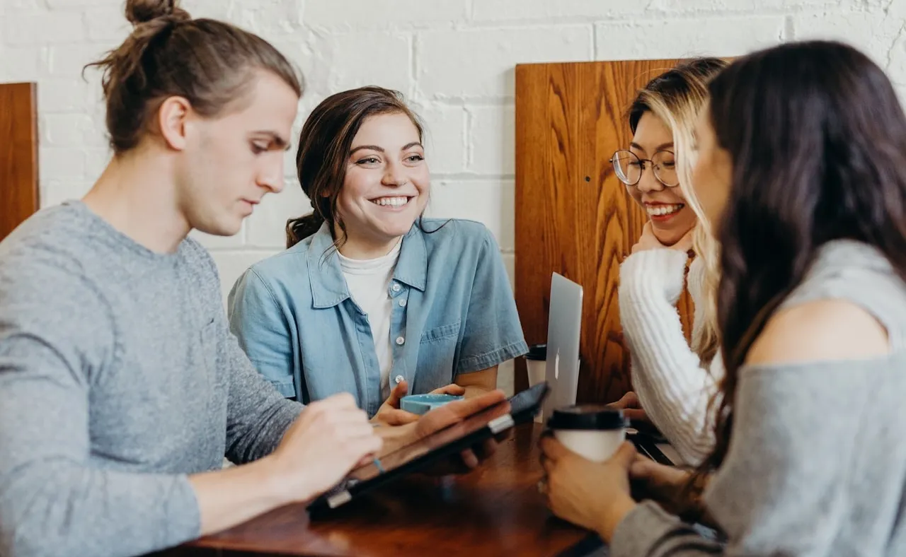 Jóvenes profesionales conversando y sonriendo alrededor de una mesa