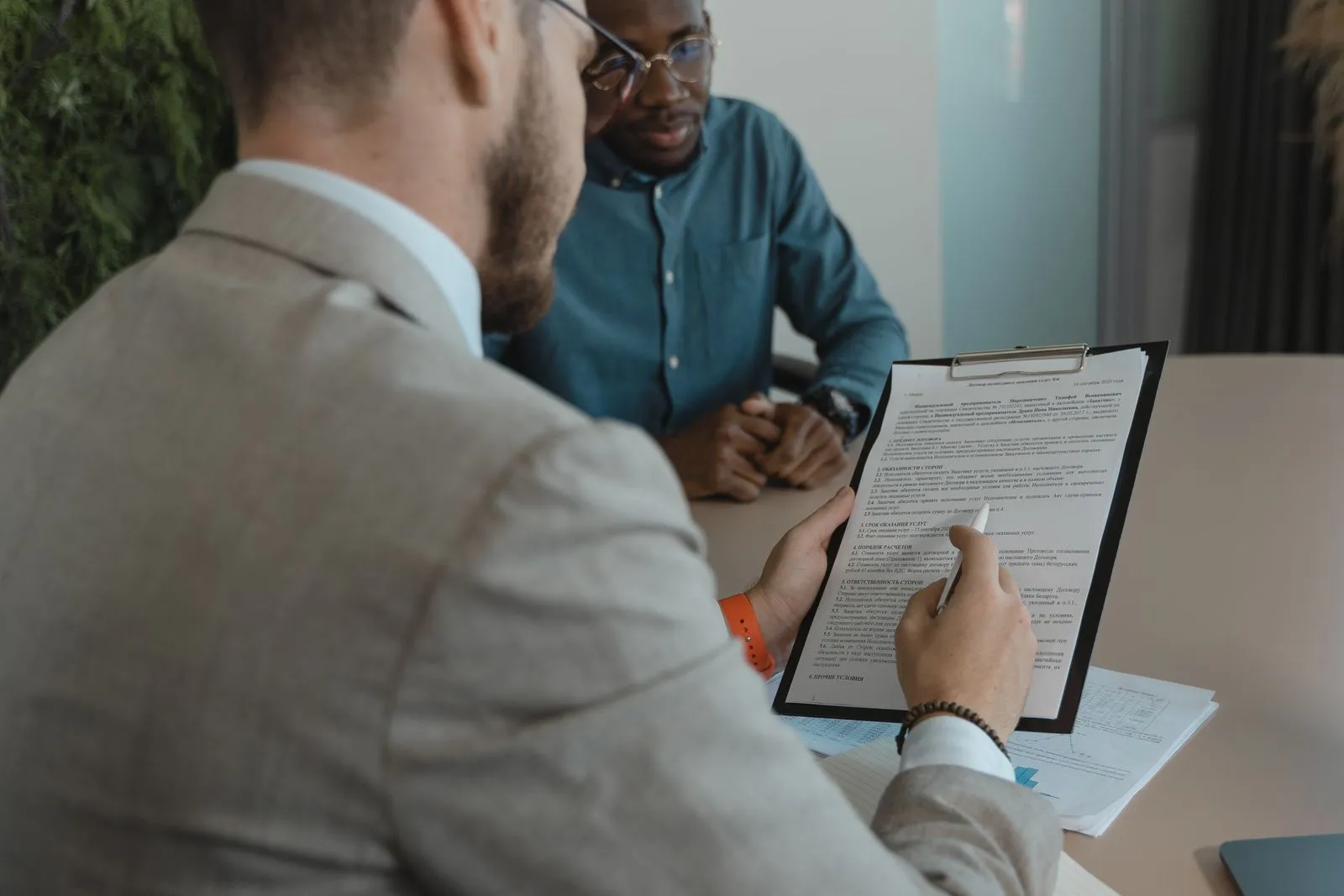 Evaluador revisando un documento junto a un profesional en una oficina